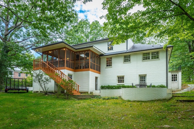 rear view of property with a sunroom, a lawn, and stairs