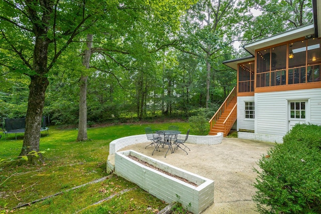 view of yard with a sunroom, a trampoline, a patio area, and stairway