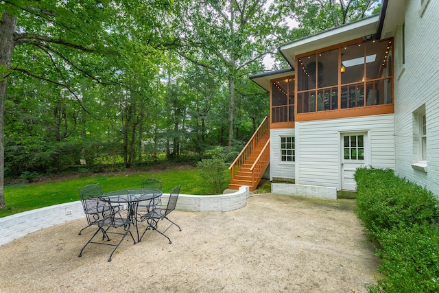 view of patio / terrace with a sunroom, outdoor dining area, and stairway