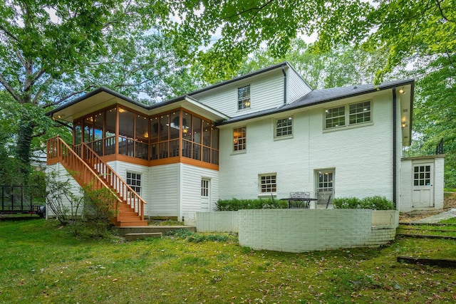 back of house featuring a sunroom, fence, a yard, brick siding, and stairs