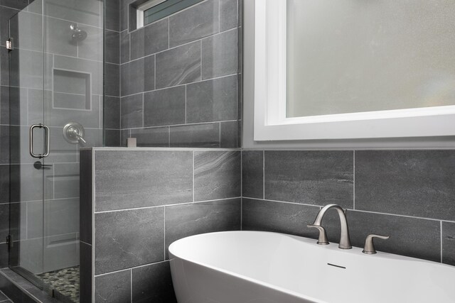 full bath with a freestanding tub, backsplash, a stall shower, and tile walls