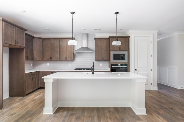 kitchen featuring built in microwave, a sink, ornamental molding, black oven, and wall chimney exhaust hood