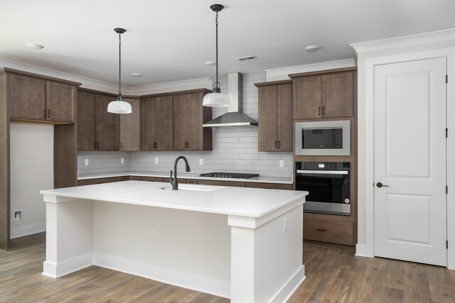 kitchen with stainless steel oven, wall chimney range hood, gas cooktop, built in microwave, and backsplash