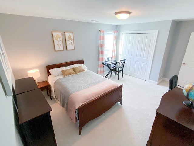 bedroom featuring baseboards, light carpet, and a closet