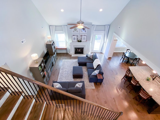 living room with a ceiling fan, a fireplace, wood finished floors, baseboards, and recessed lighting