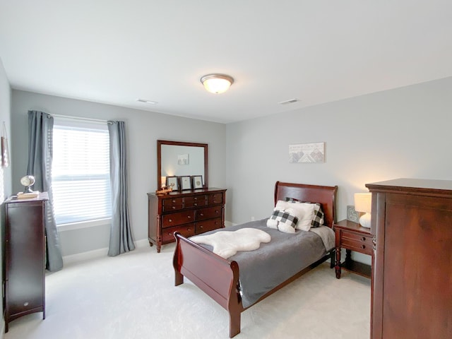 bedroom featuring baseboards, light carpet, and visible vents