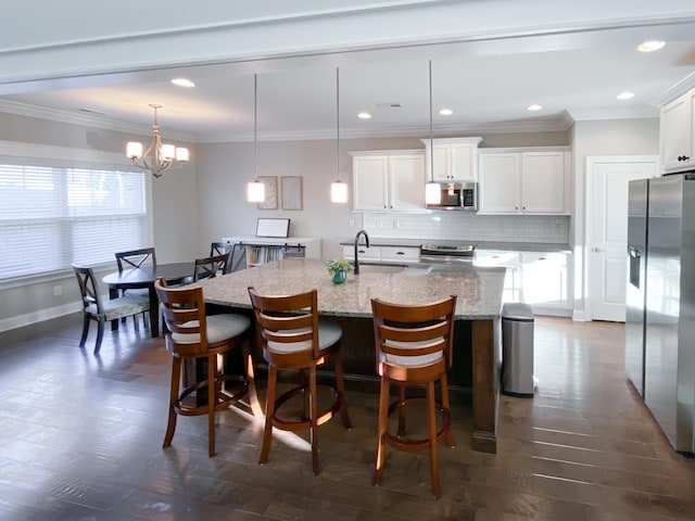 kitchen with a center island with sink, a kitchen bar, a sink, a notable chandelier, and stainless steel appliances