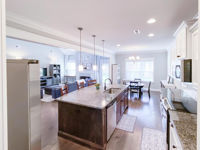 kitchen with crown molding, appliances with stainless steel finishes, a fireplace, light stone countertops, and a sink