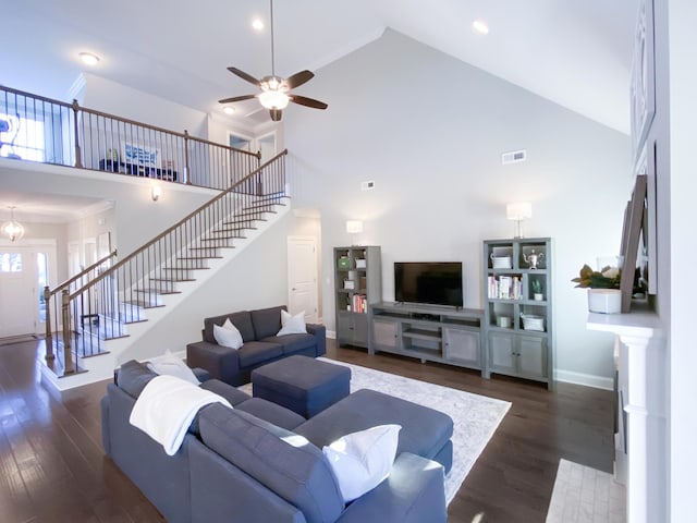 living area featuring stairs, wood finished floors, baseboards, ceiling fan, and high vaulted ceiling