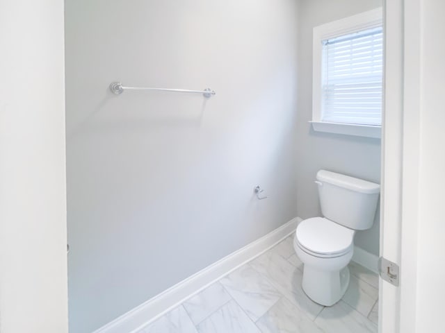 bathroom with baseboards, marble finish floor, and toilet
