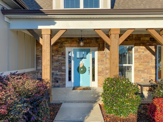 view of exterior entry with board and batten siding, a shingled roof, and stone siding