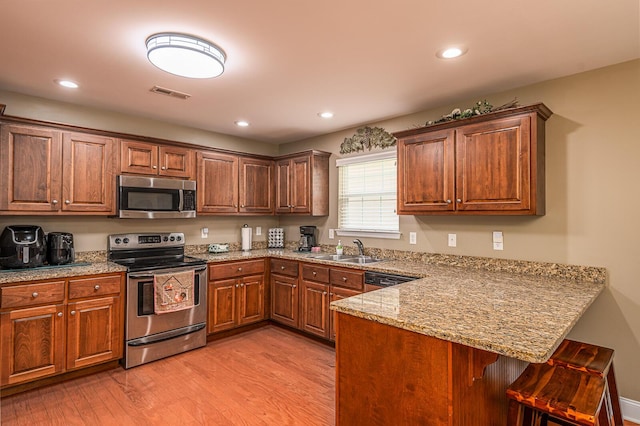 8337 Kayla Rose Cir, Ooltewah, TN 37363 - kitchen featuring stainless steel appliances, a peninsula, a breakfast bar area, light wood-style floors, and recessed lighting