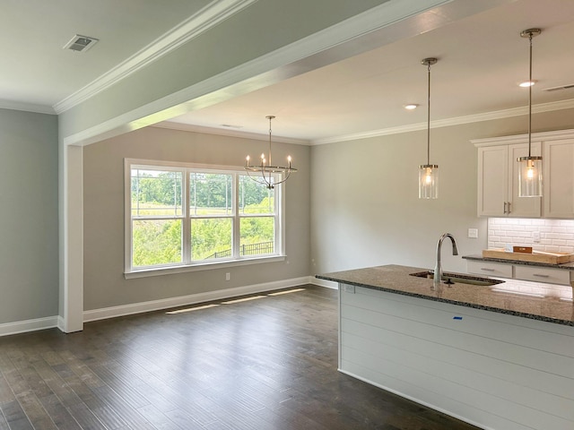 kitchen with a sink, dark stone counters, visible vents, dark wood finished floors, and baseboards