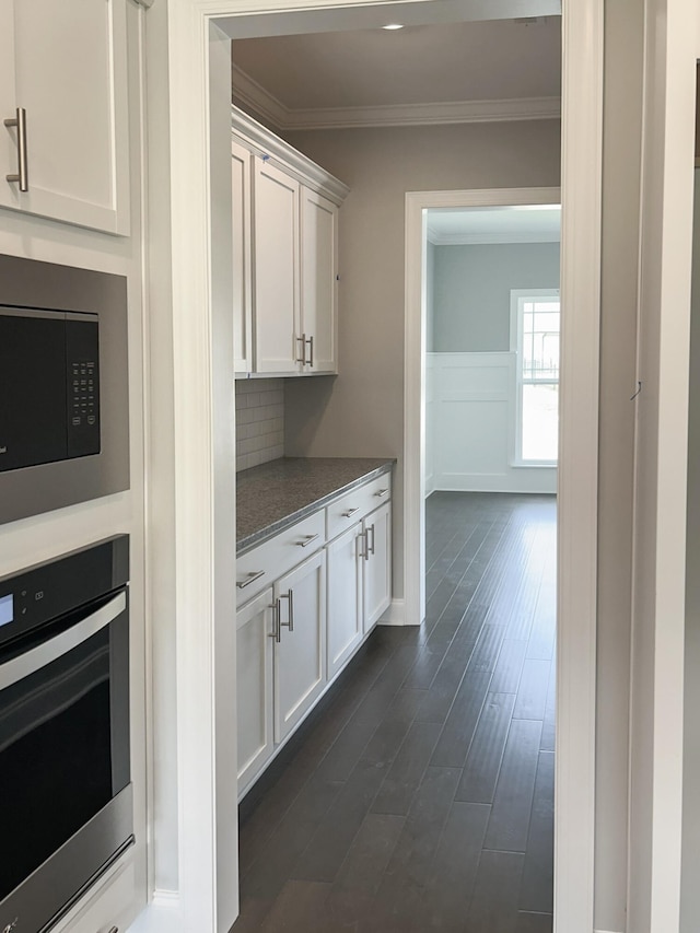 bar featuring crown molding, stainless steel appliances, dark wood-style flooring, and backsplash