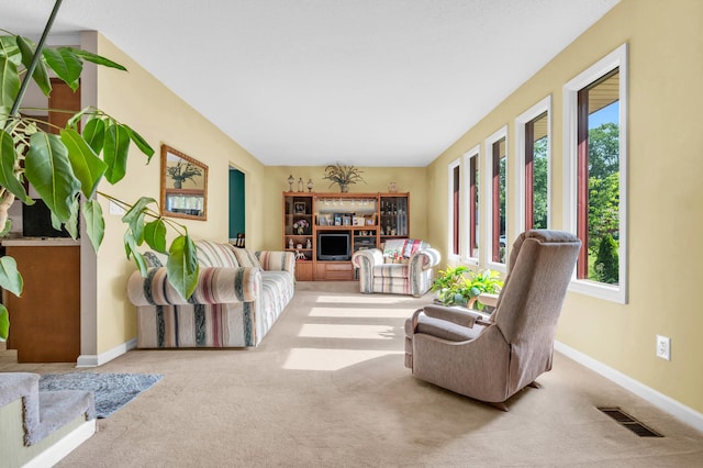 carpeted living area with plenty of natural light, baseboards, and visible vents