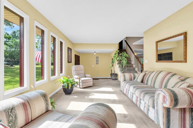 living area featuring a healthy amount of sunlight, carpet floors, baseboards, and stairway