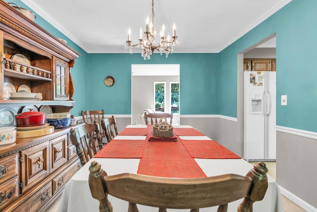 dining area featuring baseboards, ornamental molding, and a notable chandelier