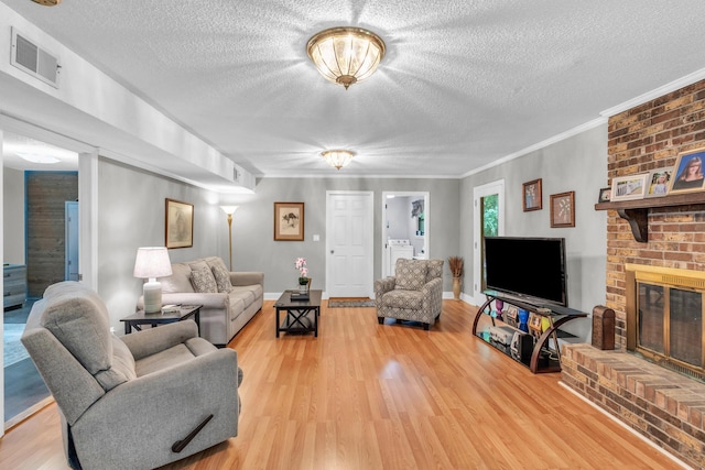 living room with washer / dryer, light wood finished floors, a textured ceiling, and visible vents