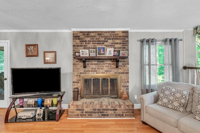 living area featuring a textured ceiling, ornamental molding, a fireplace, and wood finished floors
