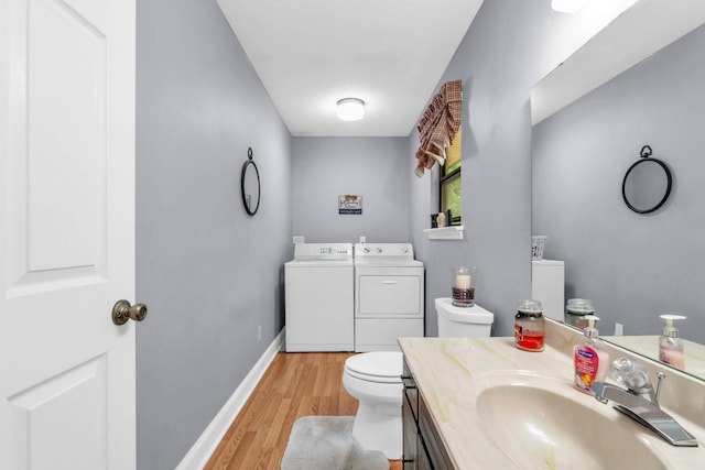 bathroom with washing machine and clothes dryer, vanity, toilet, baseboards, and wood finished floors
