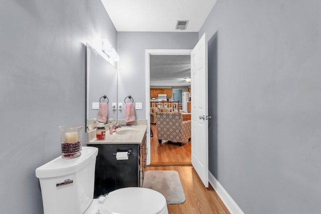 bathroom with vanity, toilet, wood finished floors, ensuite bathroom, and visible vents