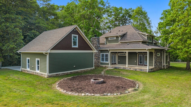 rear view of house with a shingled roof, a fire pit, a yard, and a patio area