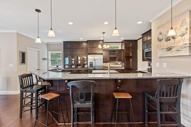 kitchen with ornamental molding, dark brown cabinets, baseboards, dark wood finished floors, and stainless steel appliances