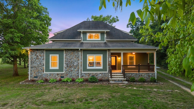 view of front facade with a porch, a front yard, and stone siding