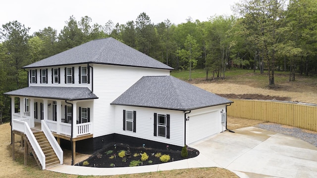 view of front of house featuring covered porch, driveway, roof with shingles, a garage, and fence