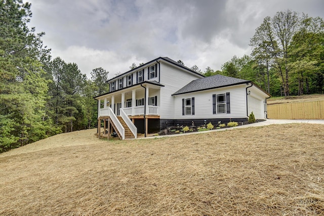 rear view of house featuring a garage, covered porch, roof with shingles, concrete driveway, and stairway
