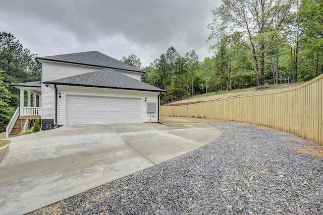 view of property exterior featuring a garage, roof with shingles, and concrete driveway