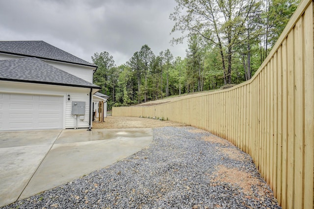 view of home's exterior featuring a garage, roof with shingles, and driveway