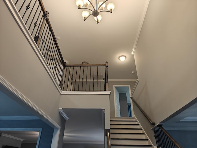 stairway featuring crown molding, a towering ceiling, and a chandelier
