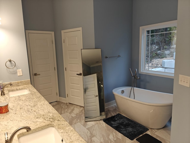 full bath featuring double vanity, a sink, marble finish floor, and a freestanding bath