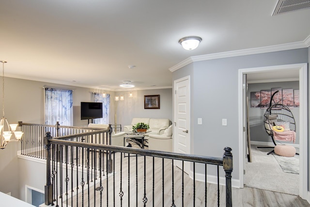 hallway featuring visible vents, ornamental molding, light wood finished floors, and an upstairs landing