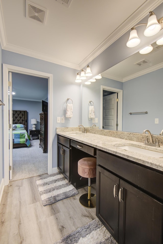 ensuite bathroom featuring visible vents, a sink, wood finished floors, and double vanity