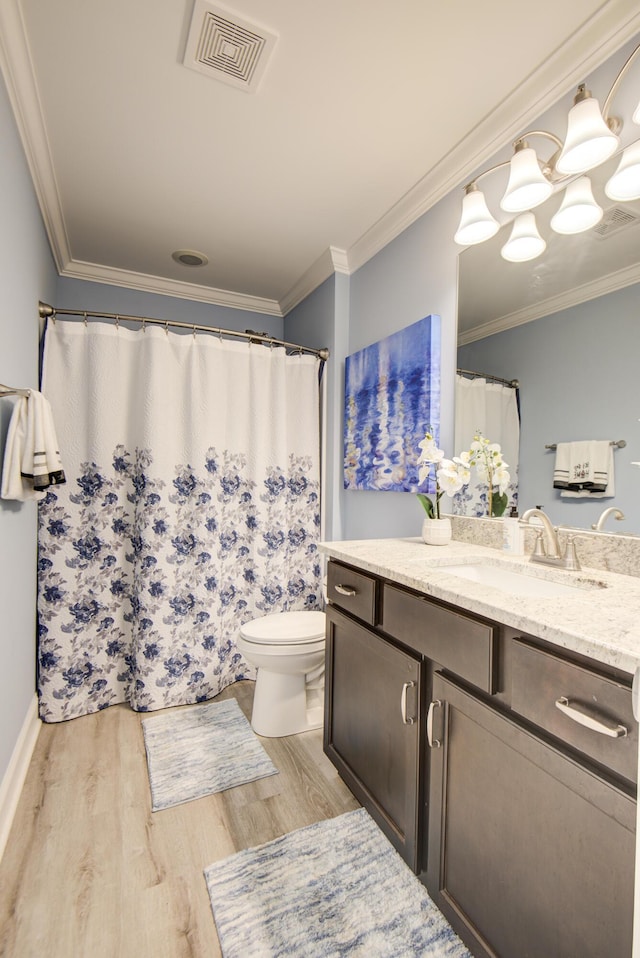 bathroom featuring visible vents, wood finished floors, vanity, toilet, and ornamental molding