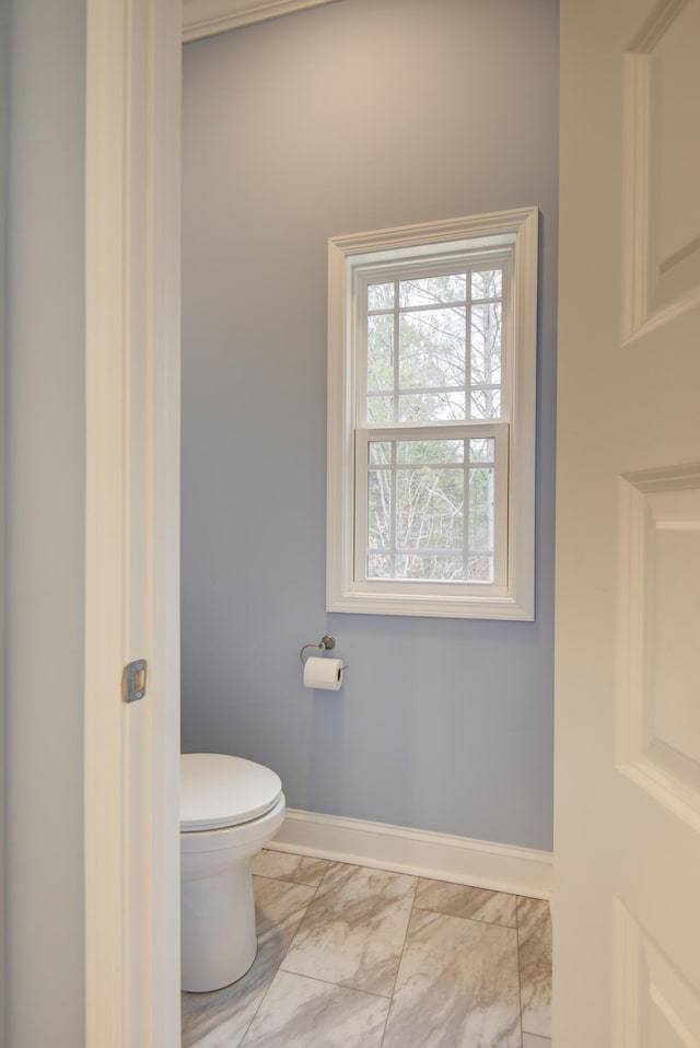 bathroom featuring baseboards, marble finish floor, and toilet
