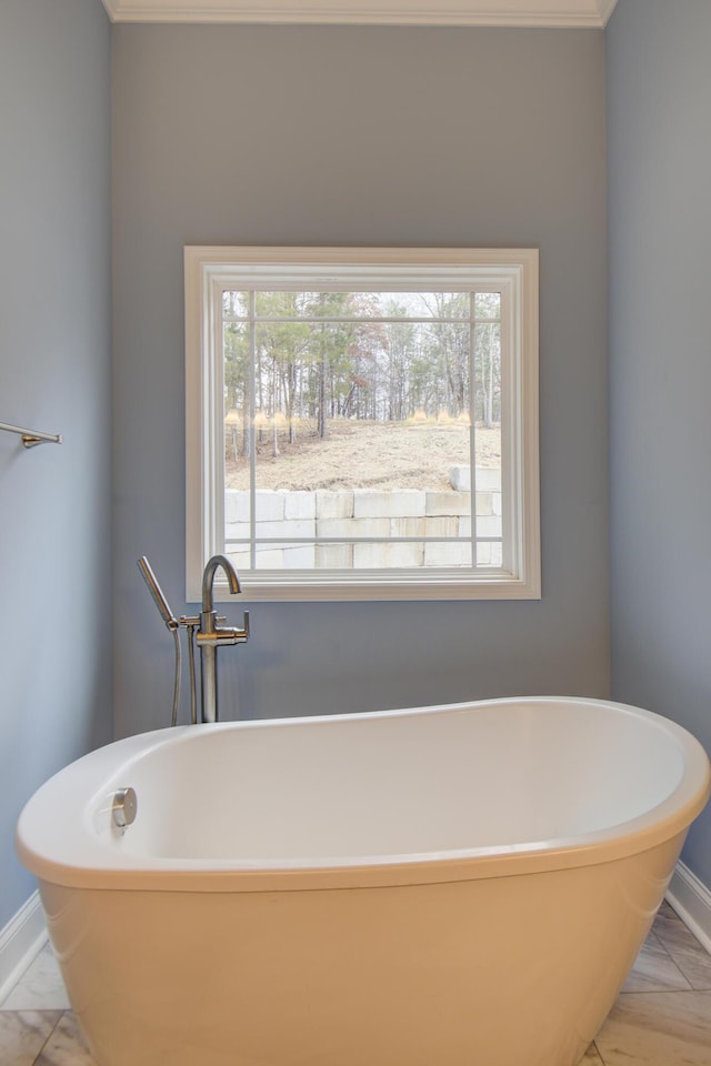 bathroom with crown molding, baseboards, and a freestanding tub