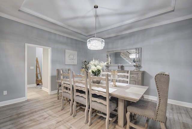 dining room with an inviting chandelier, crown molding, and light wood-style flooring