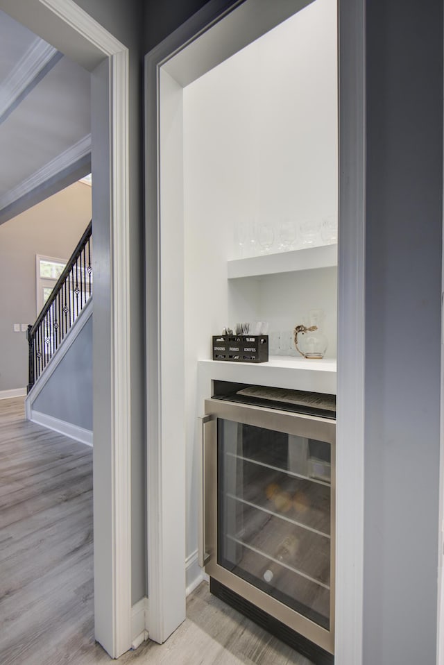 details with beverage cooler, baseboards, a dry bar, and wood finished floors