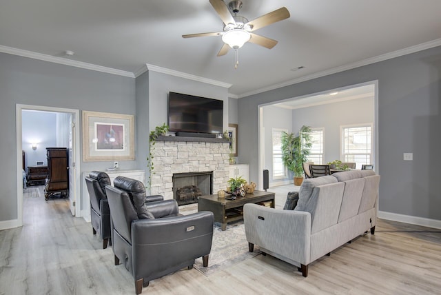 living room with a ceiling fan, crown molding, a fireplace, baseboards, and light wood-style flooring