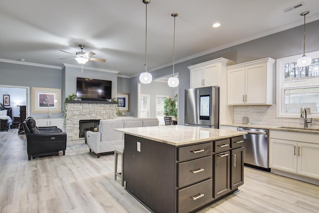 kitchen featuring white cabinets, ceiling fan, appliances with stainless steel finishes, a sink, and light wood-type flooring