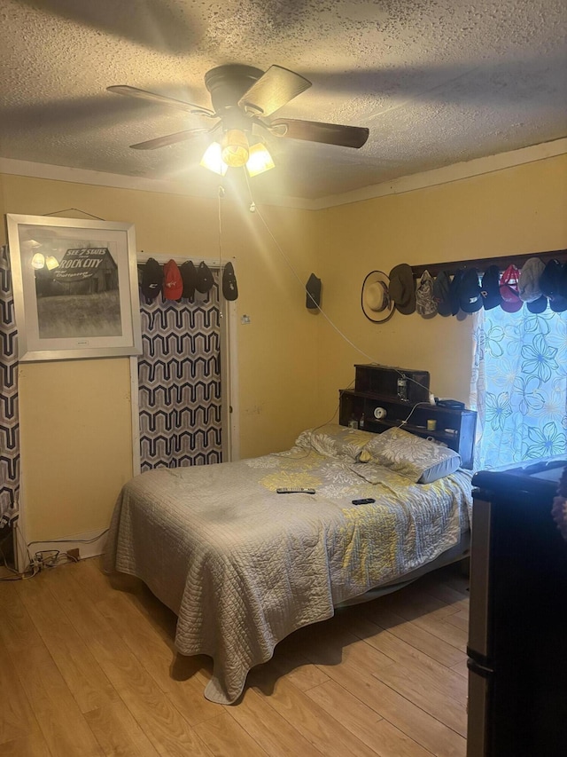 bedroom featuring ceiling fan, a textured ceiling, and wood finished floors
