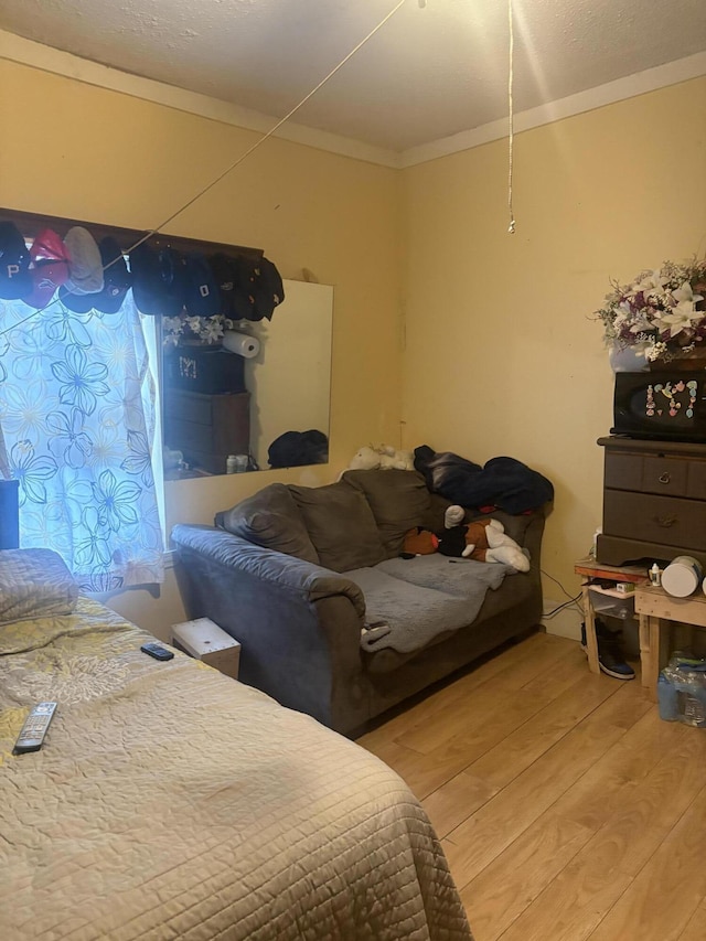 bedroom featuring ornamental molding and wood finished floors
