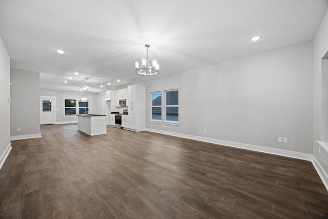 unfurnished living room with recessed lighting, a chandelier, and dark wood-type flooring