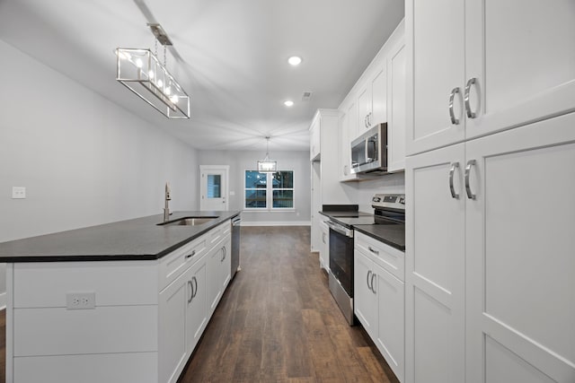 kitchen with dark countertops, recessed lighting, white cabinetry, a sink, and appliances with stainless steel finishes