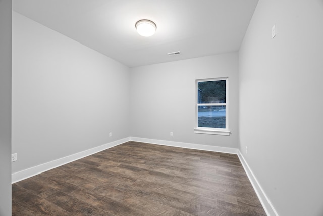 spare room with visible vents, dark wood finished floors, and baseboards