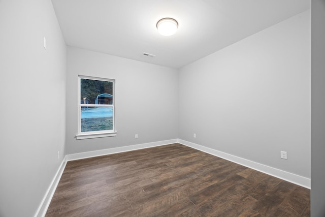 spare room with dark wood-style flooring, baseboards, and visible vents