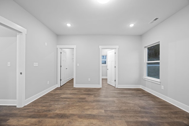 unfurnished bedroom featuring dark wood-style flooring, visible vents, and a walk in closet